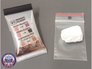 tester narkotykowy obok którego znajduje się woreczek z zapięciem strunowym, na którym leży biały proszek - amfetamina