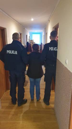 zatrzymana kobieta stoi w towarzystwie dwóch policjantów