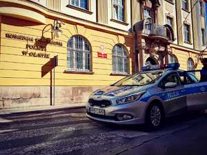 zdjęcie przedstawia radiowóz zaparkowany przy budynku Komendy Powiatowej Policji w Oławie