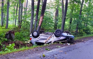 samochód osobowy marki VW Golf leżący w przydrożnym rowie, bo uderzeniu w drzewo