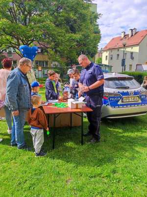 policjant podczas festynu rozdaje dzieciom elementy odblaskowe oraz balony