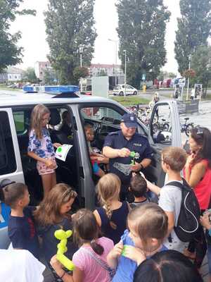 policjant rozdaje dzieciom elementy odblaskowe oraz gadżety