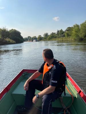 na zdjęciu policjant na łodzi OSP kontroluje stan rzeki Odry oraz sprawdza czy przestrzegane są zakazy
