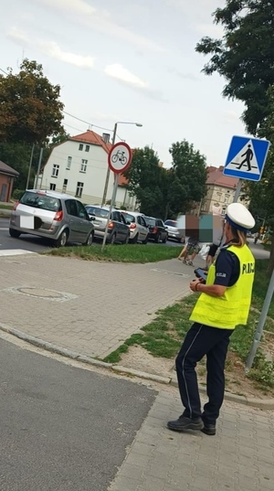 na zdjęciu funkcjonariusz ruchu drogowego sprawdza przestrzeganie przepisów przez pieszych i rowerzystów