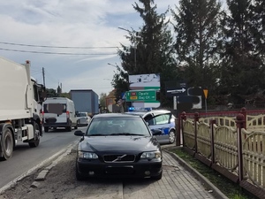 Godzikowice, droga krajowa nr 94. Na chodniku stoi samochód osobowy marki Volvo a za nim policyjny oznakowany radiowóz