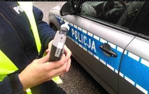 policjant stojący przy oznakowanym radiowozie podczas kontroli stanu trzeźwości - zdjęcie poglądowe