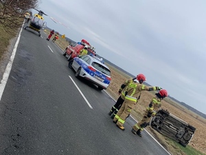 policjanci oraz funkcjonariusze Straży Pożarnej podczas akcji ratunkowej dotyczącej dachowania samochodu osobowego