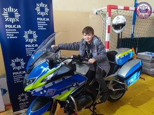 chłopiec siedzący na motocyklu policyjnym