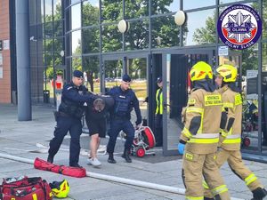 policjanci wyprowadzający osobę agresywną, która podczas akcji ratunkowej zaatakowała strażaka - ćwiczenia dowódczo-sztabowe pn. CESiR 2023 -  Jelcz Laskowice