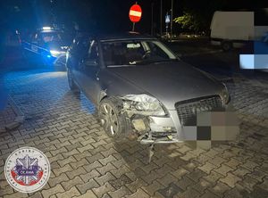 samochód marki audi koloru srebrnego z uszkodzeniami po zderzeniu z latarnią
