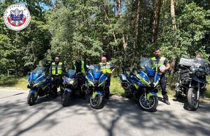 cztery policyjne motocykle obok których stoją Policjanci z Wydziału Ruchu Drogowego