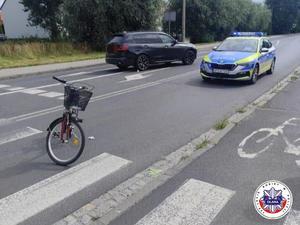na drodze stoi oznakowany radiowóz, czarne SUV marki BMW oraz na przejściu dla pieszych rower typu damka.