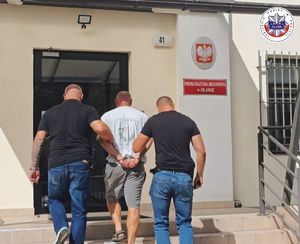 policjanci prowadzą zatrzymanego mężczyznę