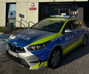 policyjny oznakowany radiowóz przy budynku komisariatu