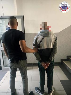 policjant kryminalny prowadzący osobę zatrzymaną