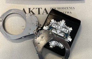 okładka od teczki akta sprawy, kajdanki oraz policyjna gwiazda