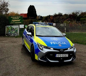 policyjny radiowóz zaparkowany przy wejściu na teren ogrodów działkowych