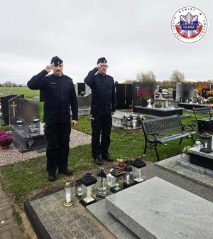 Komendanci oddający hołd przy grobie zmarłego kolegi