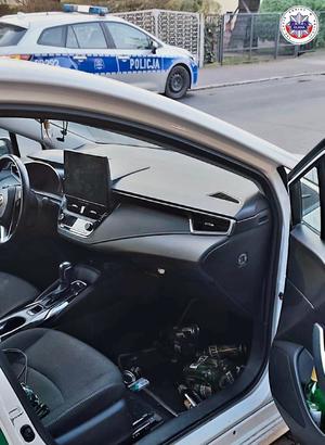 wnętrze samochodu z puszkami piwa oraz radiowóz w tle