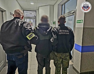 Policjant i funkcjonariusz Straży Granicznej prowadzą osobę zatrzymaną