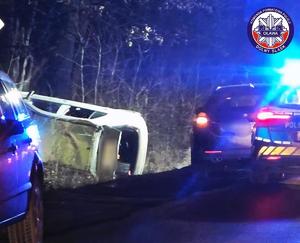 samochód po dachowaniu, w tle radiowóz policji