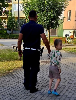 Policjant prowadzący za rękę 5-letniego chłopca