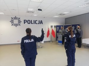 zdjęcie przedstawia dwóch policjantów stojących twarzą do Sztandaru Komendy Powiatowej Policji w Oławie podczas Roty Ślubowania